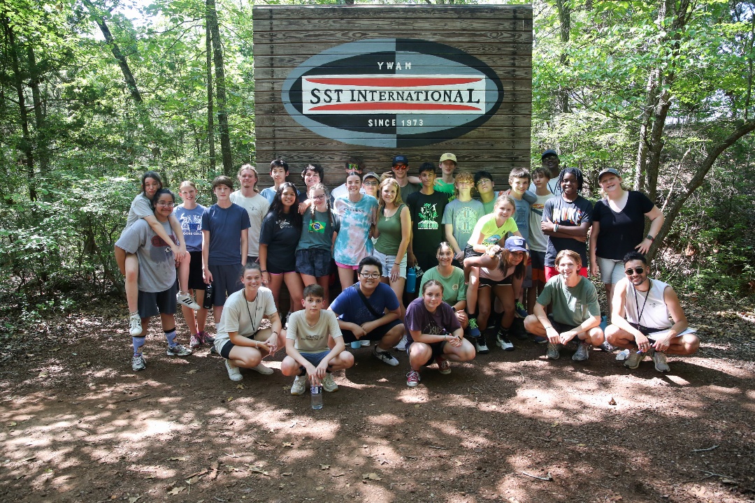 Group of students taking a picture outside underneath the SST logo.