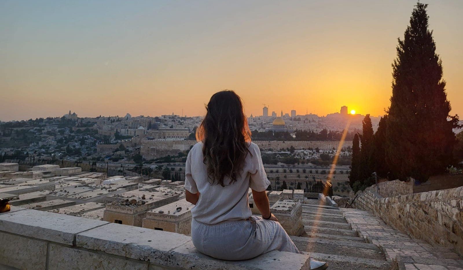 girl sitting looking over israel during sunset